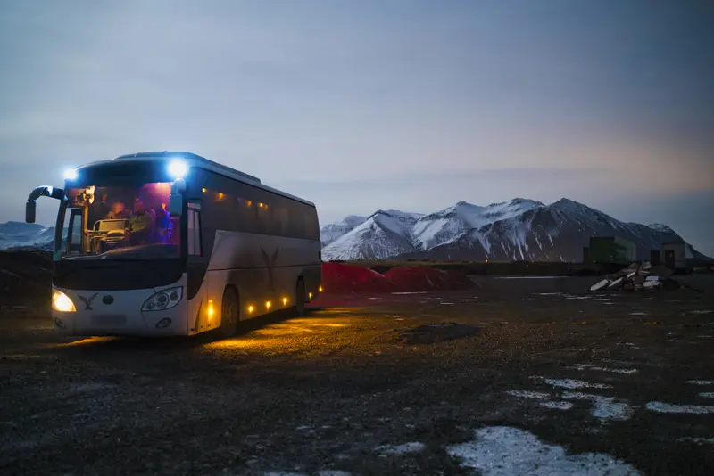 Autobus s upaljenim svjetlima u sumrak, spreman za vožnju